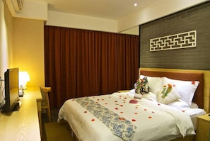 Een hotelkamer met een bed, een bureau, een stoel en een wand met een geometrisch patroon.