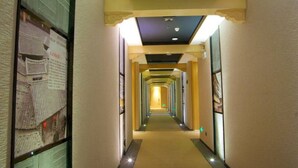 Ein Hotelgang mit einem zentralen Weg, gesäumt von Wänden mit gerahmten Bildern.