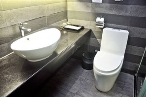 Een moderne badkamer met een witte wasbak, toilet en een zwarte prullenbak.