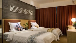 Ein Hotelzimmer mit zwei Betten, einer Wand aus Ziegelsteinen, einem Holzkopfteil und einem Vorhang am Fenster.