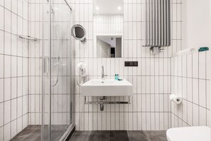 A modern bathroom with a glass shower enclosure, a white sink with a mirror above it, and a toilet. - Vinfort Aparthotel - Krakow Old Town (Kraków)