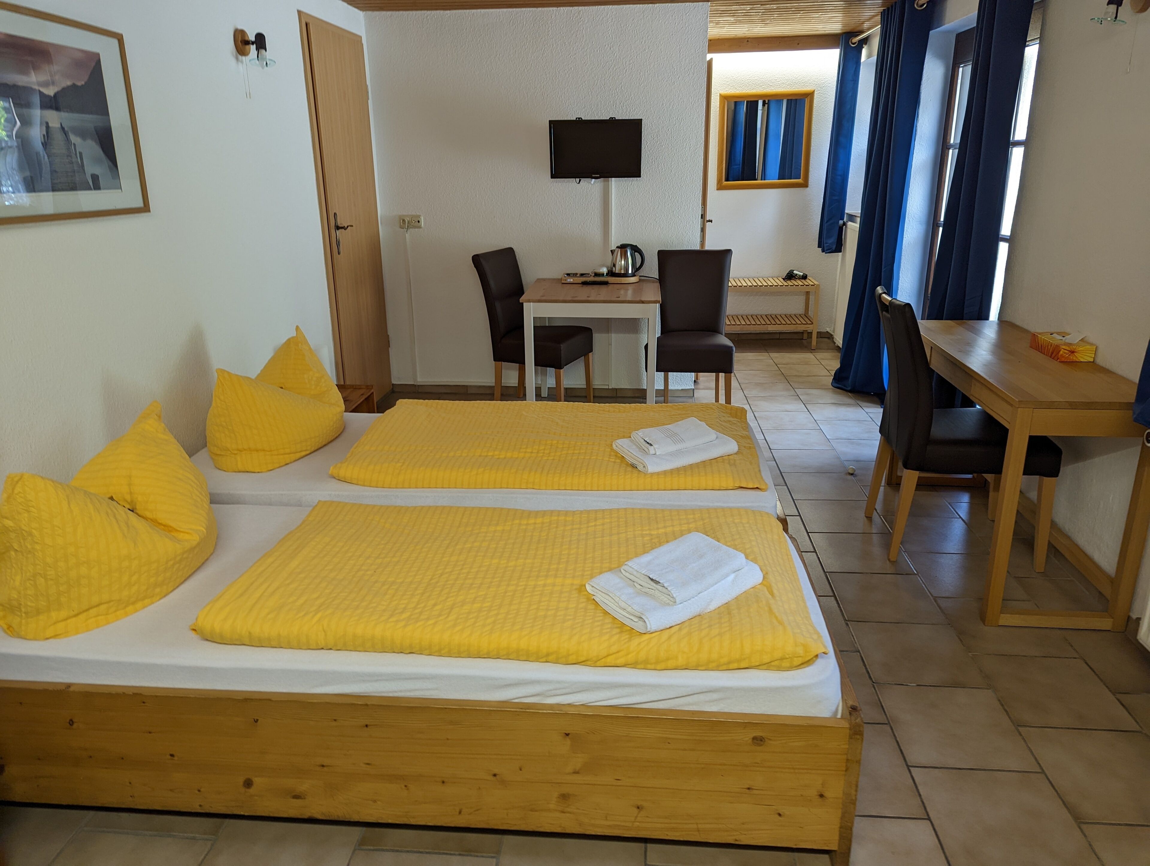 A hotel room with two beds, a desk, a chair, and a television.