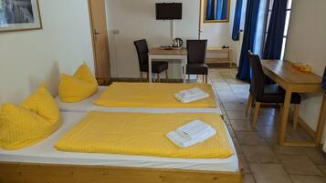 Ein Hotelzimmer mit zwei Betten, einem Schreibtisch, einem Stuhl und einem Fernseher.