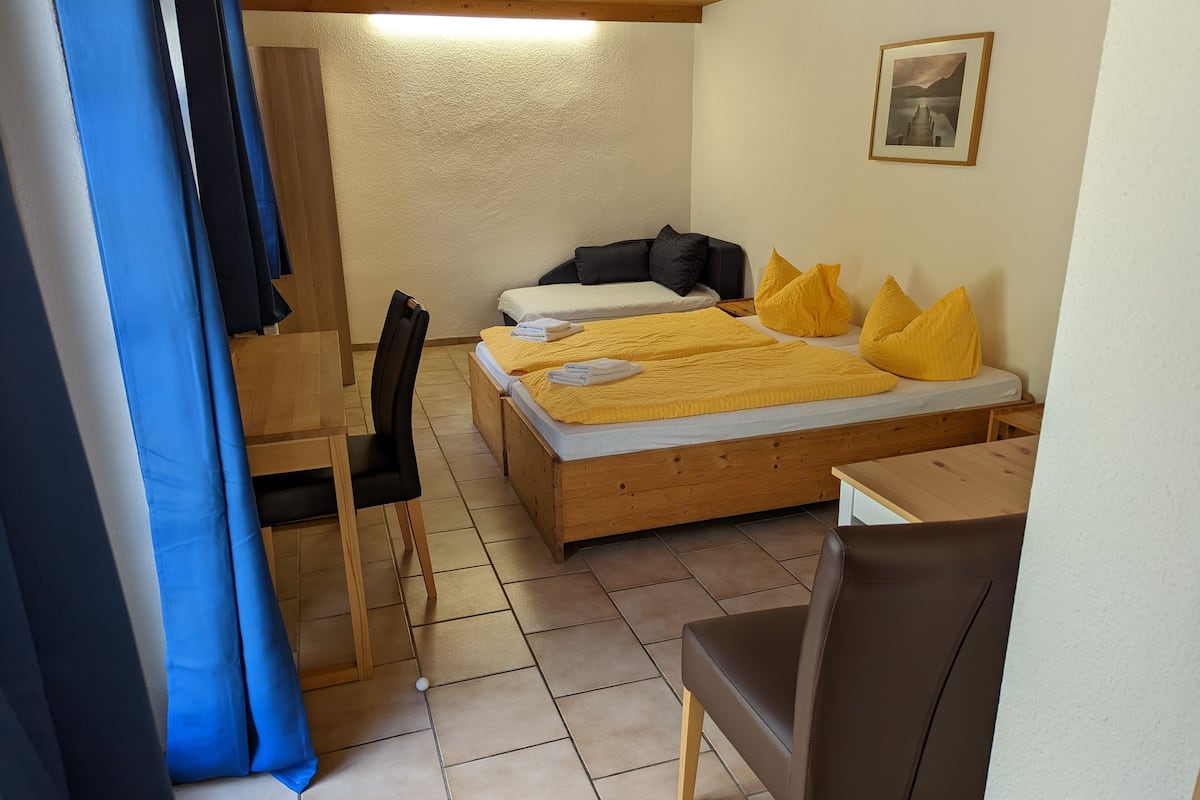 A small, cozy room with a bed, a chair, and a desk.