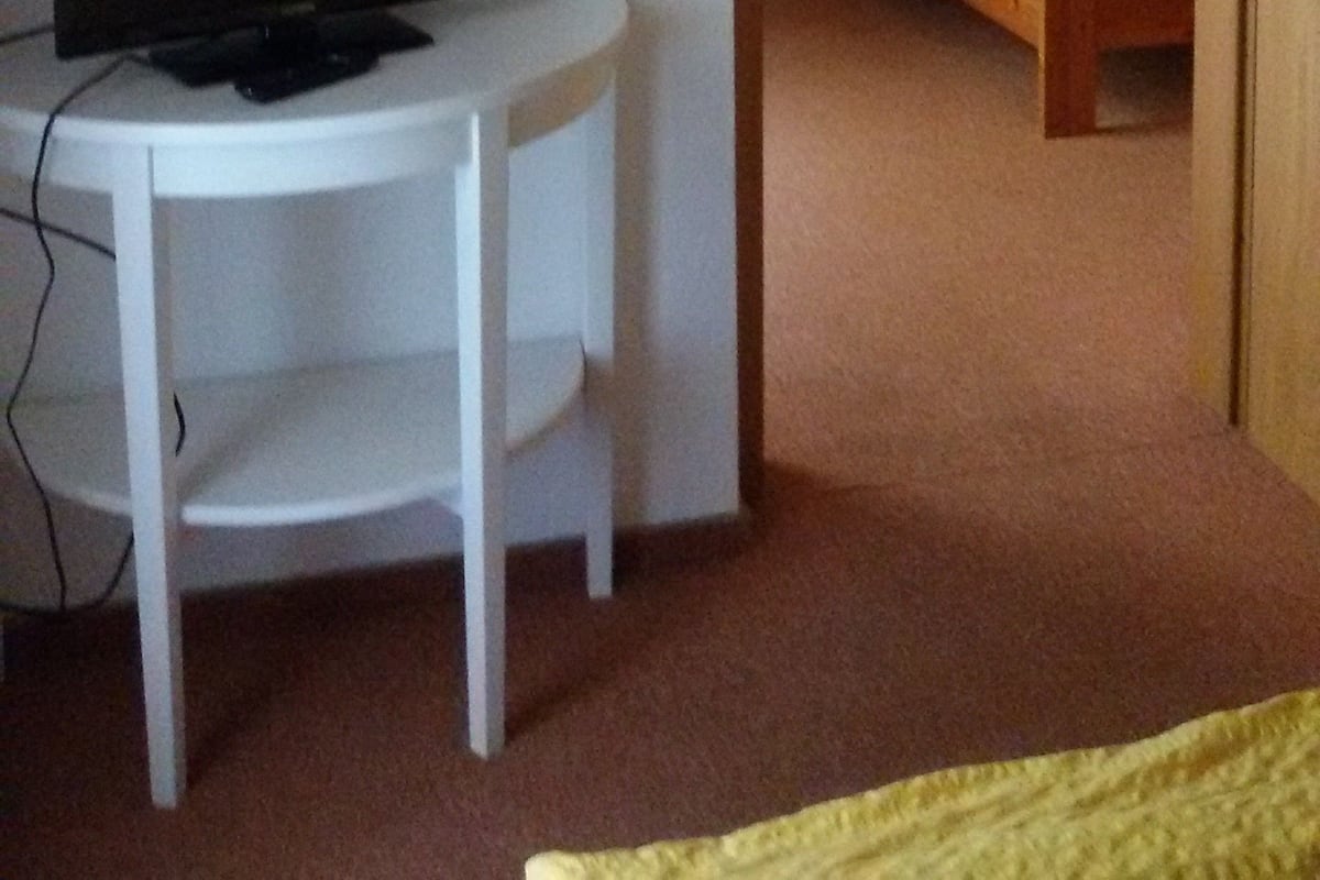 A small room with a bed, a desk, and a television.