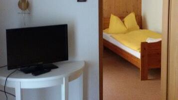 A small room with a bed, a desk, and a television.