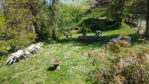Un jardin avec un espace aménagé pour s’asseoir à l’extérieur, un banc en pierre et une plante en pot.