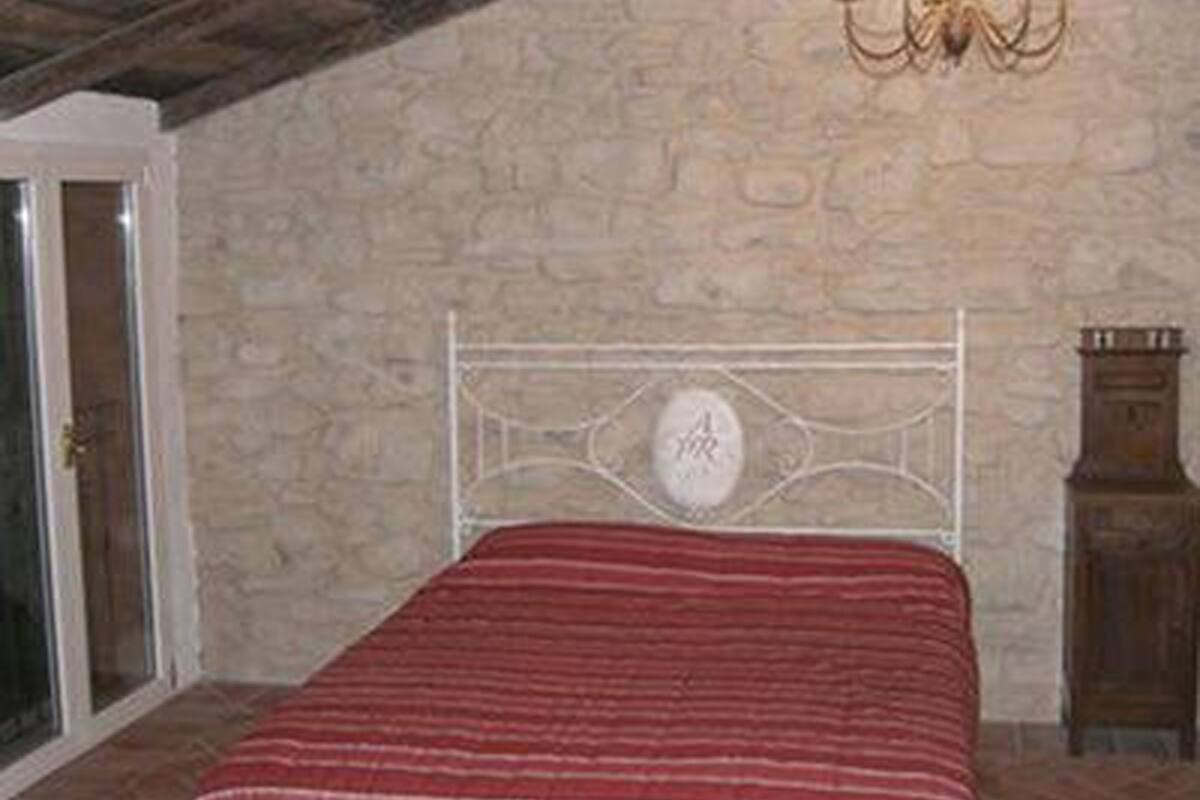 Ein Schlafzimmer mit einer Steinwand, einem Metallbettgestell und einem Holzkabinent.