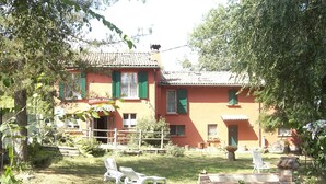 Un bâtiment à deux étages, doté d’un toit en tuiles, d’un balcon et d’un jardin aménagé avec des espaces de détente en plein air.
