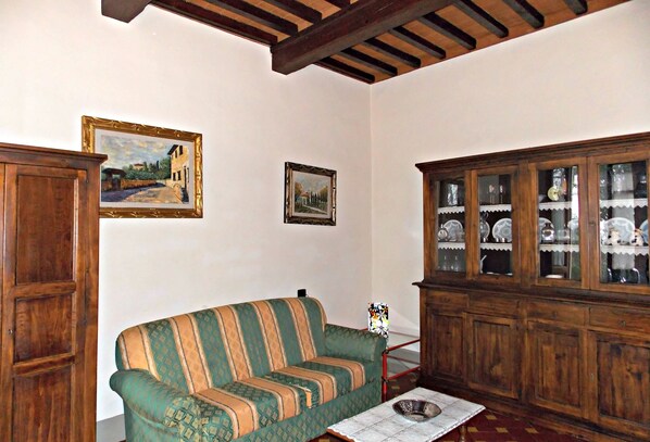 A room with a green sofa, wooden cabinets, and two framed paintings on the wall. - Il Villino (Vicchio)