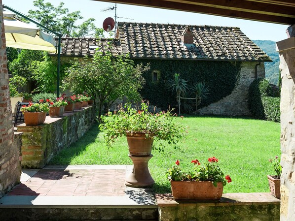 A courtyard with a stone wall, potted plants, and a tiled roof. - Villa Eleonora (Dicomano)