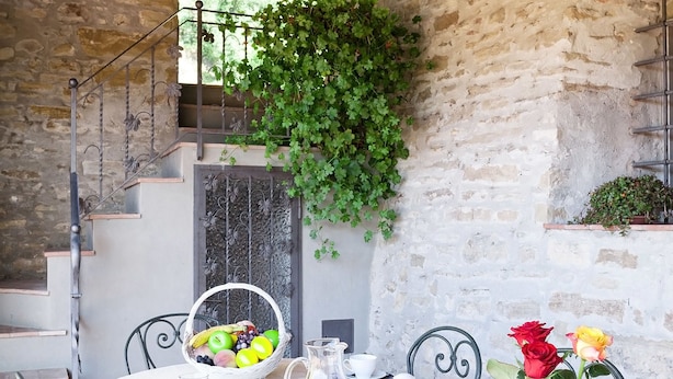 A rustic outdoor dining area with a stone wall, a staircase, and a hanging plant. - Villa Eleonora (Dicomano)
