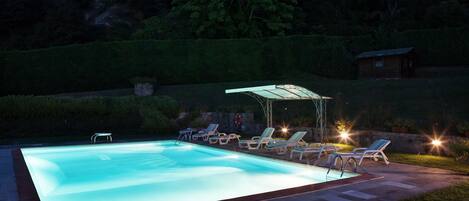 Una piscina con sillas de descanso y un área de estar techada.