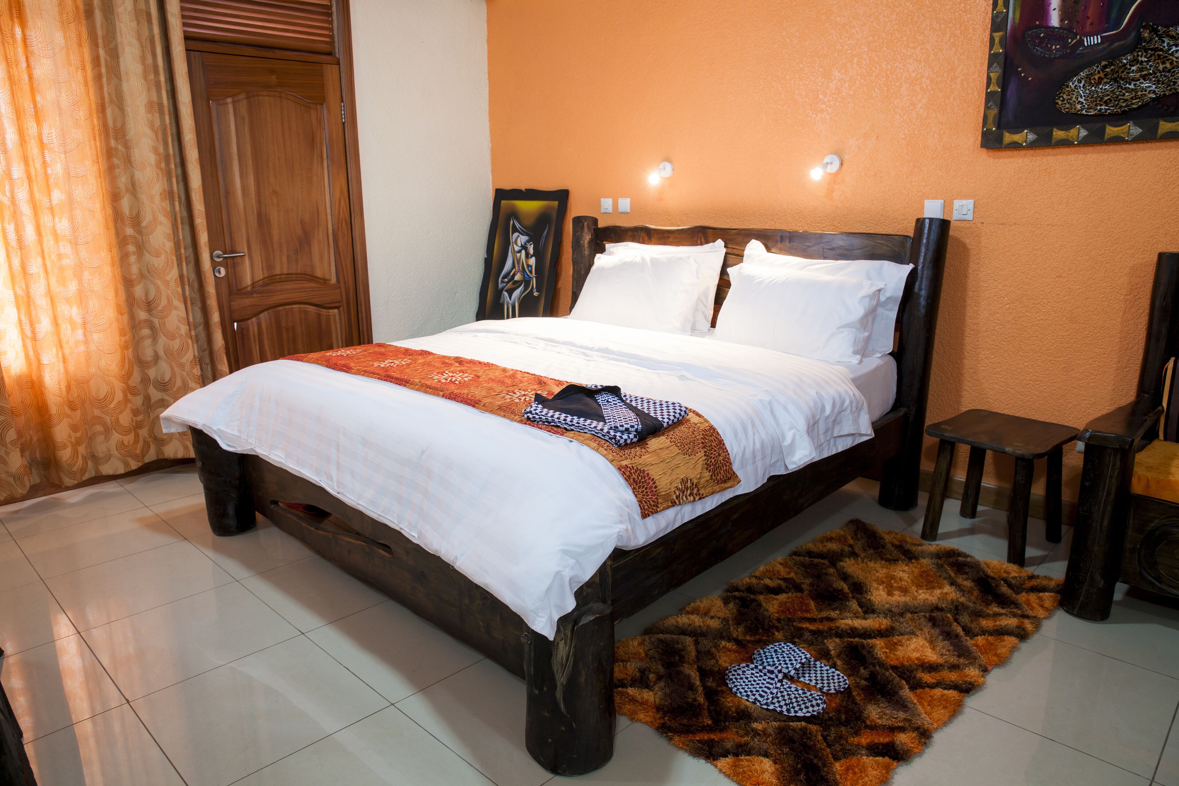 A bedroom with a wooden bed, white bedding, a brown rug, and a painting on the wall.