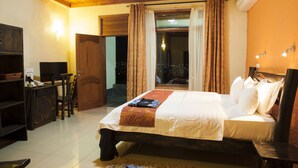 A hotel room with a bed, a desk, a chair, a TV, and a window with curtains. - Select Boutique Hotel (Kigali)