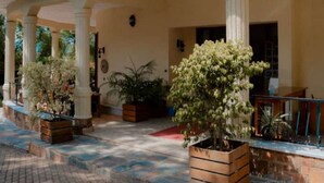 A covered outdoor area with columns, potted plants, and a paved walkway. - Select Boutique Hotel (Kigali)