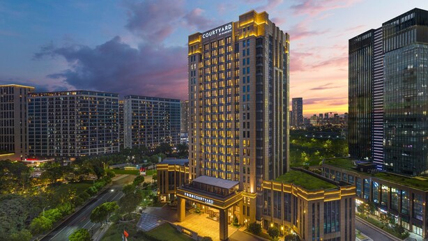 A high-rise hotel with a prominent 'Courtyard by Marriott' sign, surrounded by other buildings and a well-maintained green space. - Courtyard by Marriott Hangzhou Xiaoshan (Hangzhou)