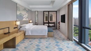 A modern hotel room with a large bed, a desk, a TV, and a balcony with a city view. - Courtyard by Marriott Hangzhou Xiaoshan (Hangzhou)
