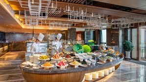 A buffet setup with chefs preparing food, surrounded by a modern interior with a marble floor and contemporary lighting fixtures. - Courtyard by Marriott Hangzhou Xiaoshan (Hangzhou)