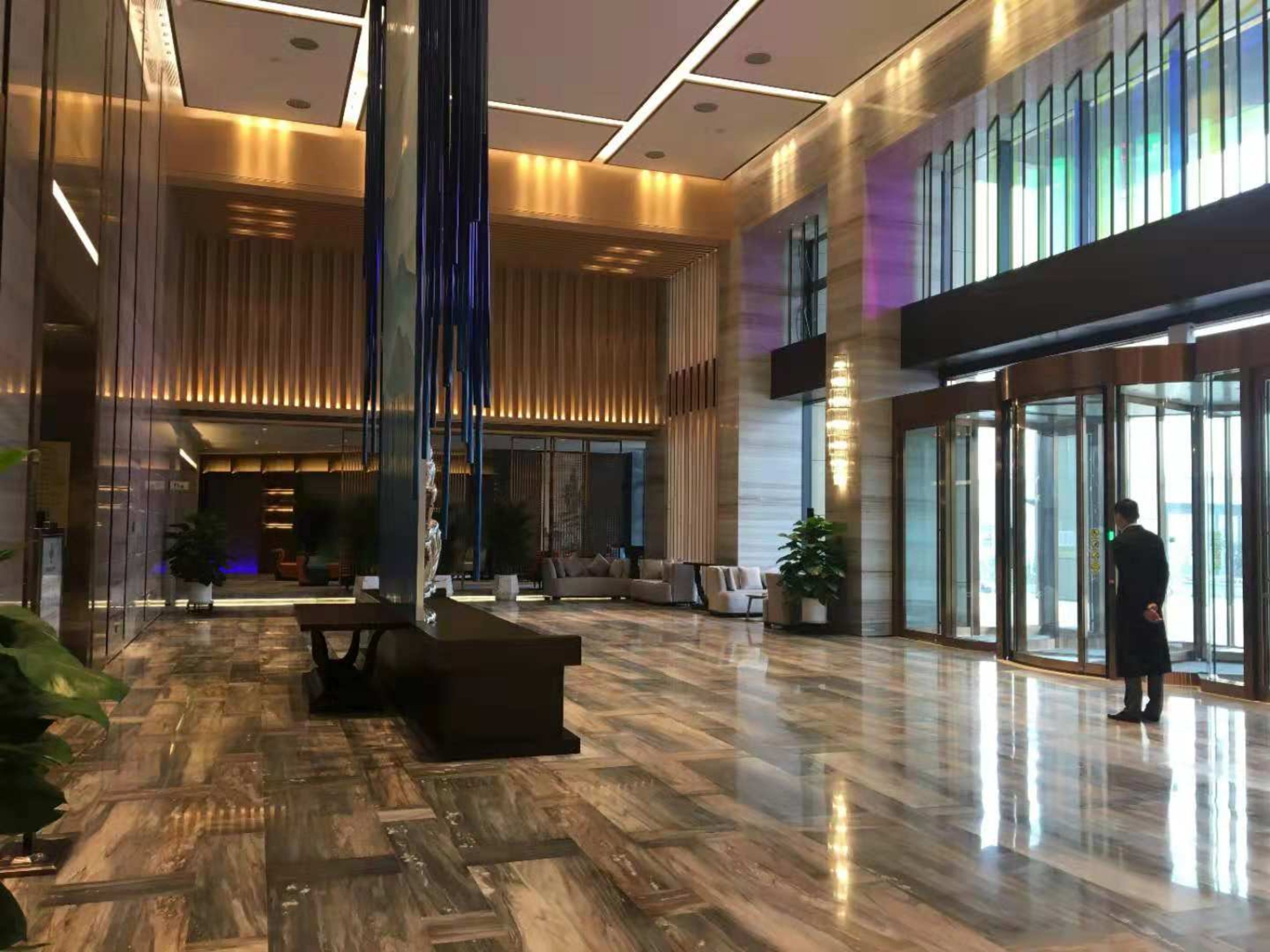 Un hall d’entrée spacieux, doté d’un plancher en bois poli, de coins salon et d’une grande entrée en verre.