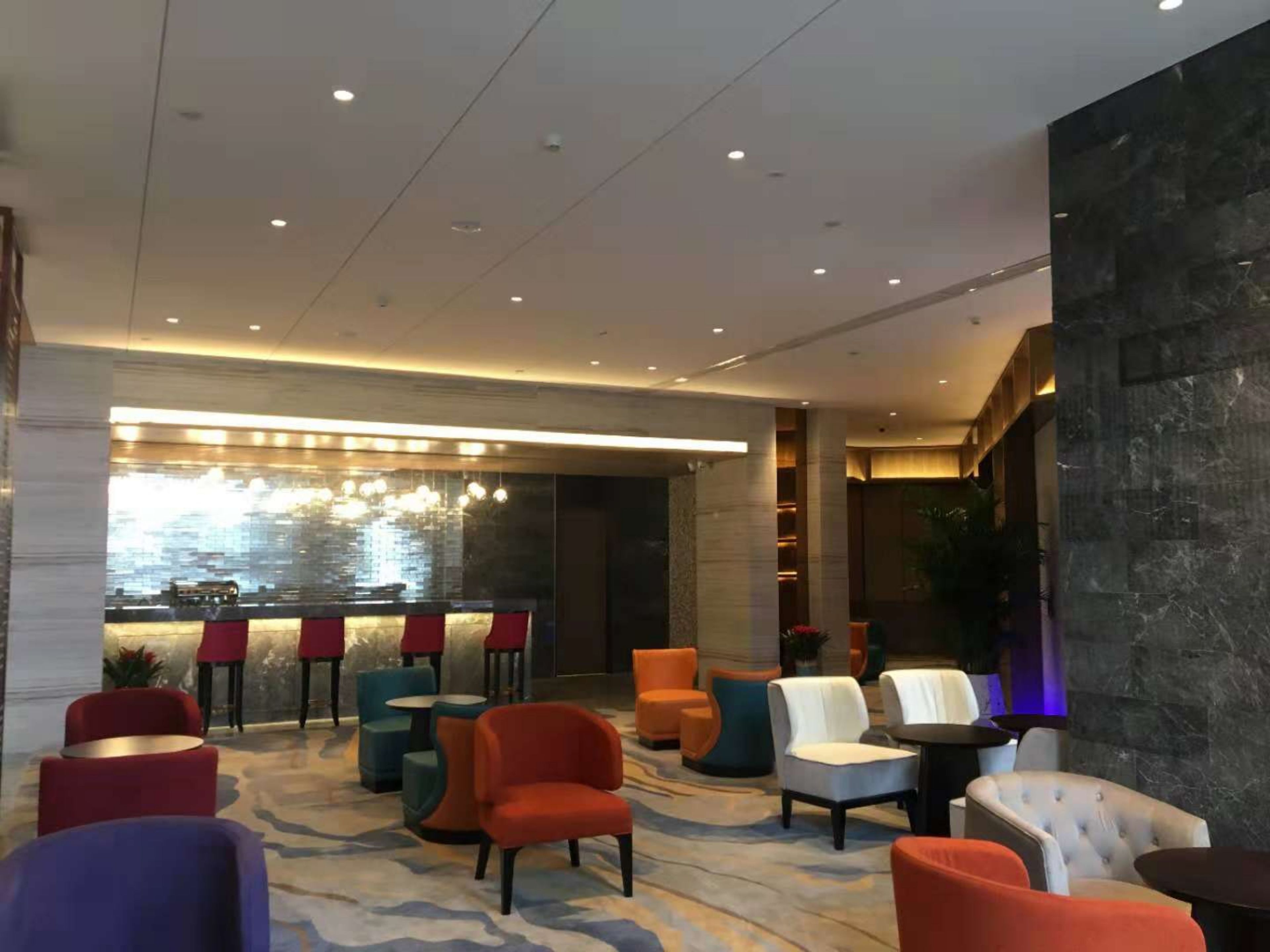 A modern lobby with a bar area, comfortable seating, and a decorative wall.