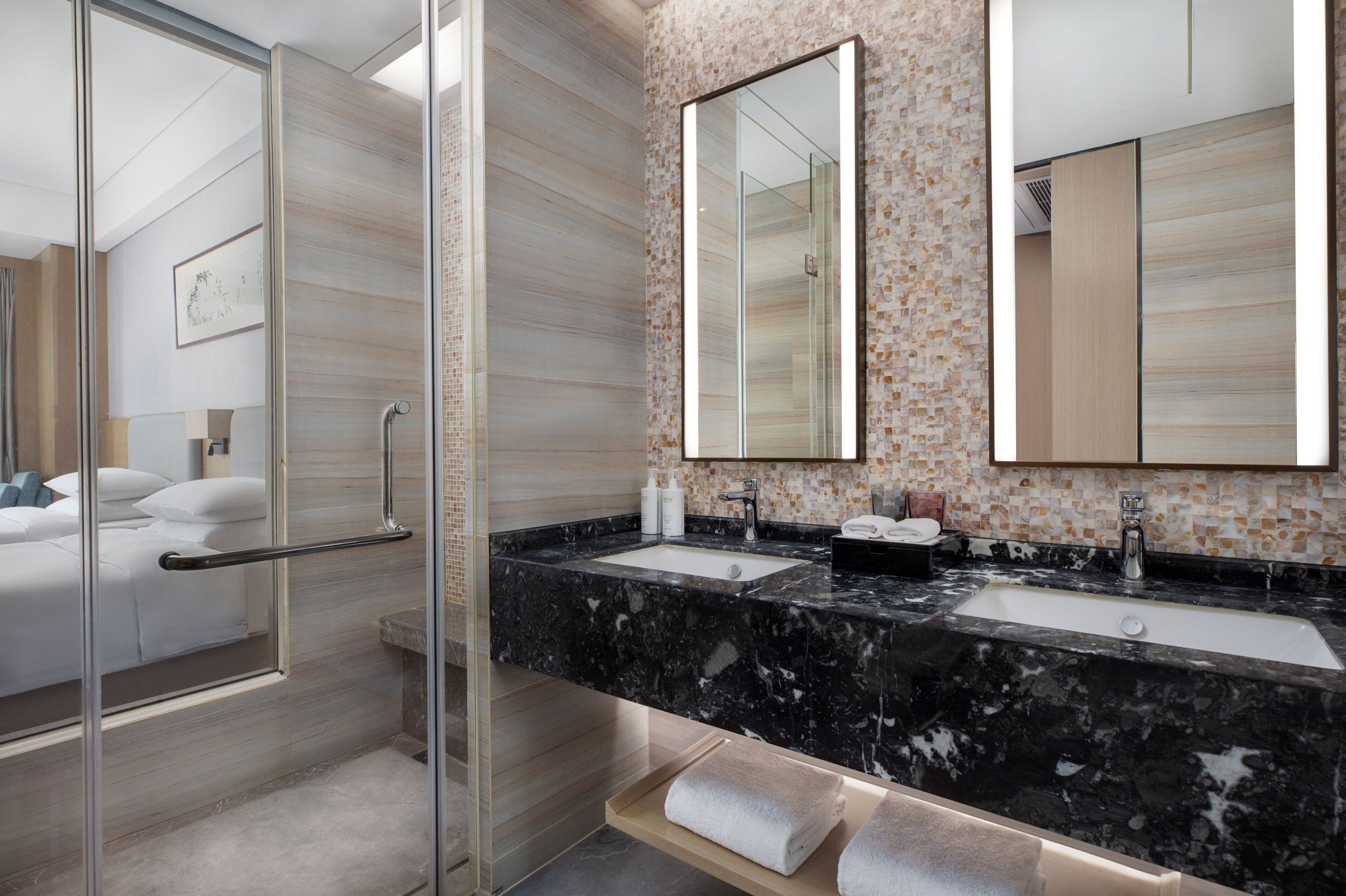 A modern bathroom with a glass shower enclosure, a marble sink, and a large mirror.
