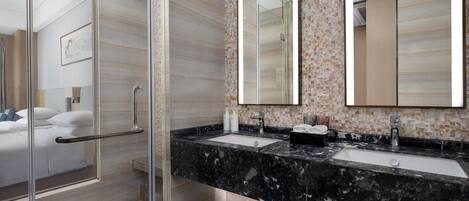 A modern bathroom with a glass shower enclosure, a marble sink, and a large mirror.
