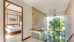 A bedroom with a bed, a desk, and a large window with a view of greenery. - Villa Palavee A2 (Krabi)