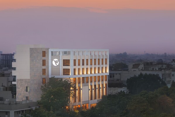 Un edificio moderno con un logotipo destacado, varios pisos y una fachada combinada de vidrio y piedra.