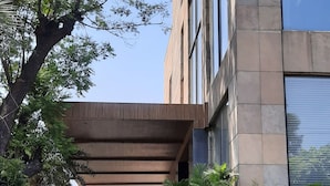 Entrada de un edificio moderno con un corredor cubierto, plantas en macetas y un letrero que indica la ubicación de Jalandhar Fortune JIOTIC hotel en Jalandhar.
