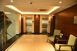 A lobby with a glass staircase, elevators, and seating area with a small table and flowers. - Fortune Avenue, Jalandhar -  Member ITC Hotels' Group (Jalandhar)