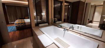 A modern bathroom with a large bathtub, a mirror, and a shower area.