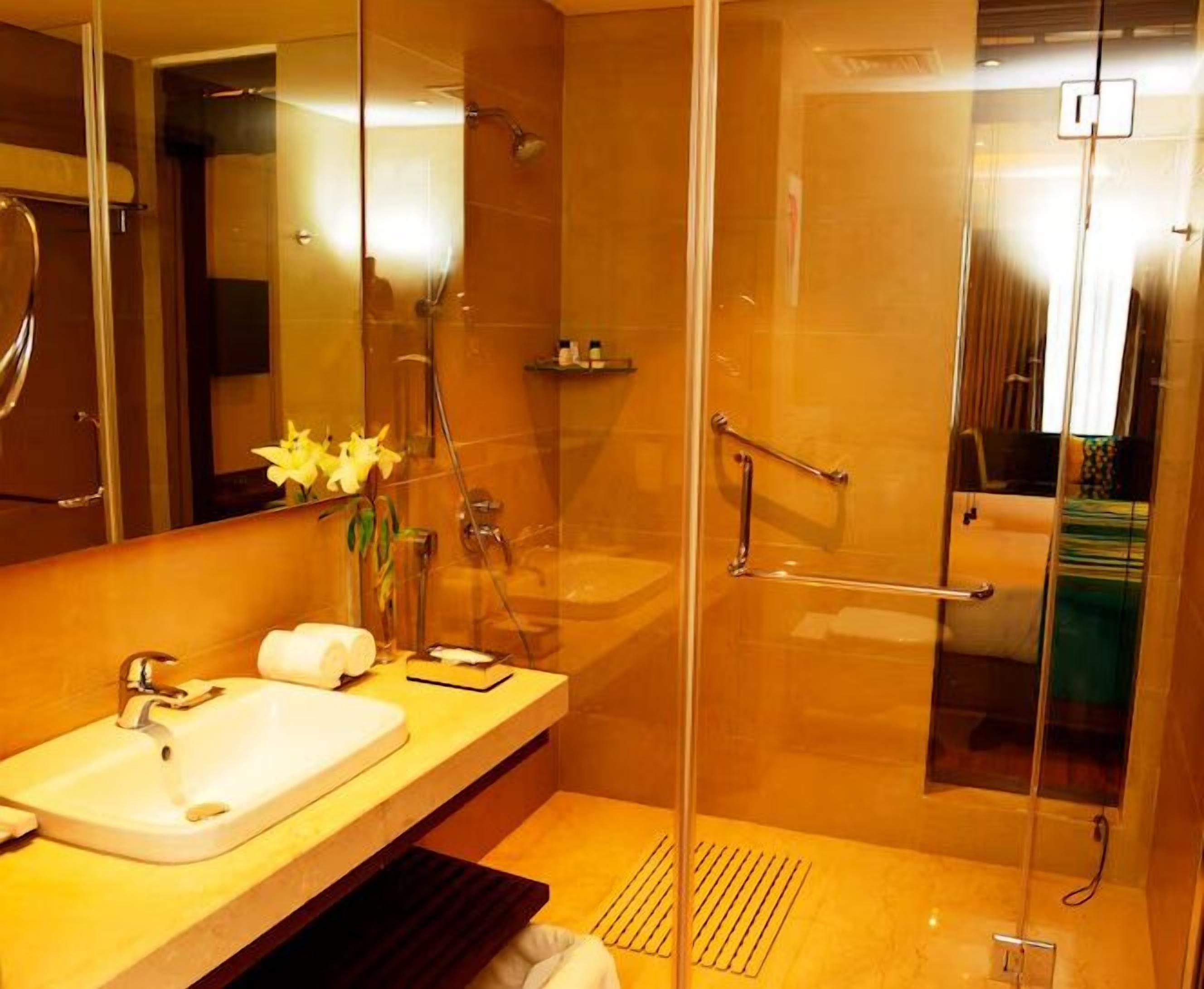 Une salle de bain moderne avec une douche à parois de verre, un lavabo avec un miroir et un porte-serviettes.