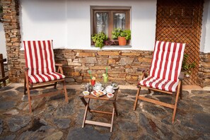 Two striped chairs with a table set for breakfast, a stone wall, and a window with plants. - El Paraje del Chef (Nevada)