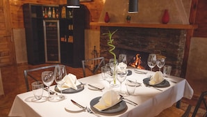 Una mesa de comedor lista para una comida con una chimenea al fondo.