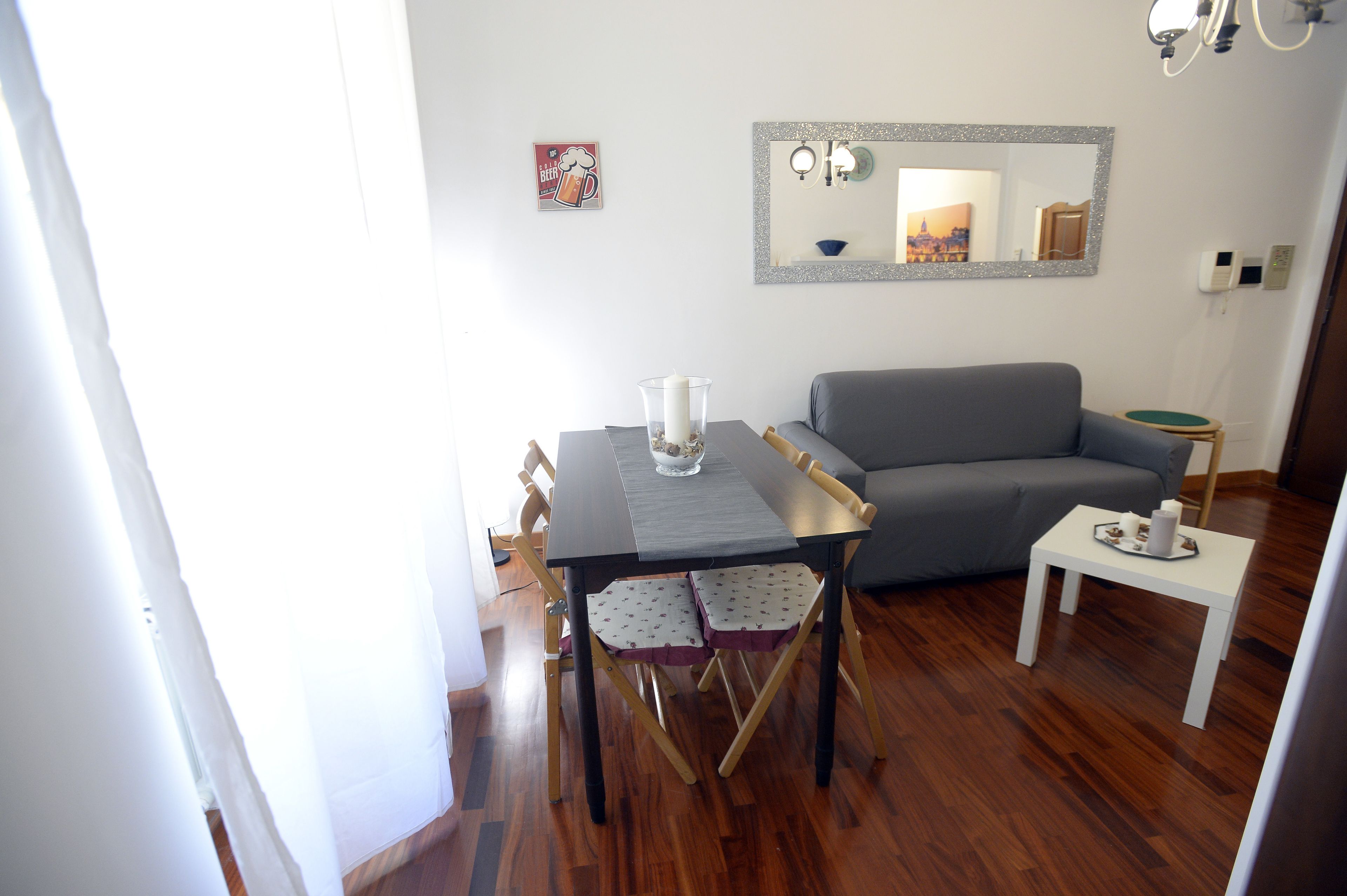 A dining area with a table, chairs, and a small white table.