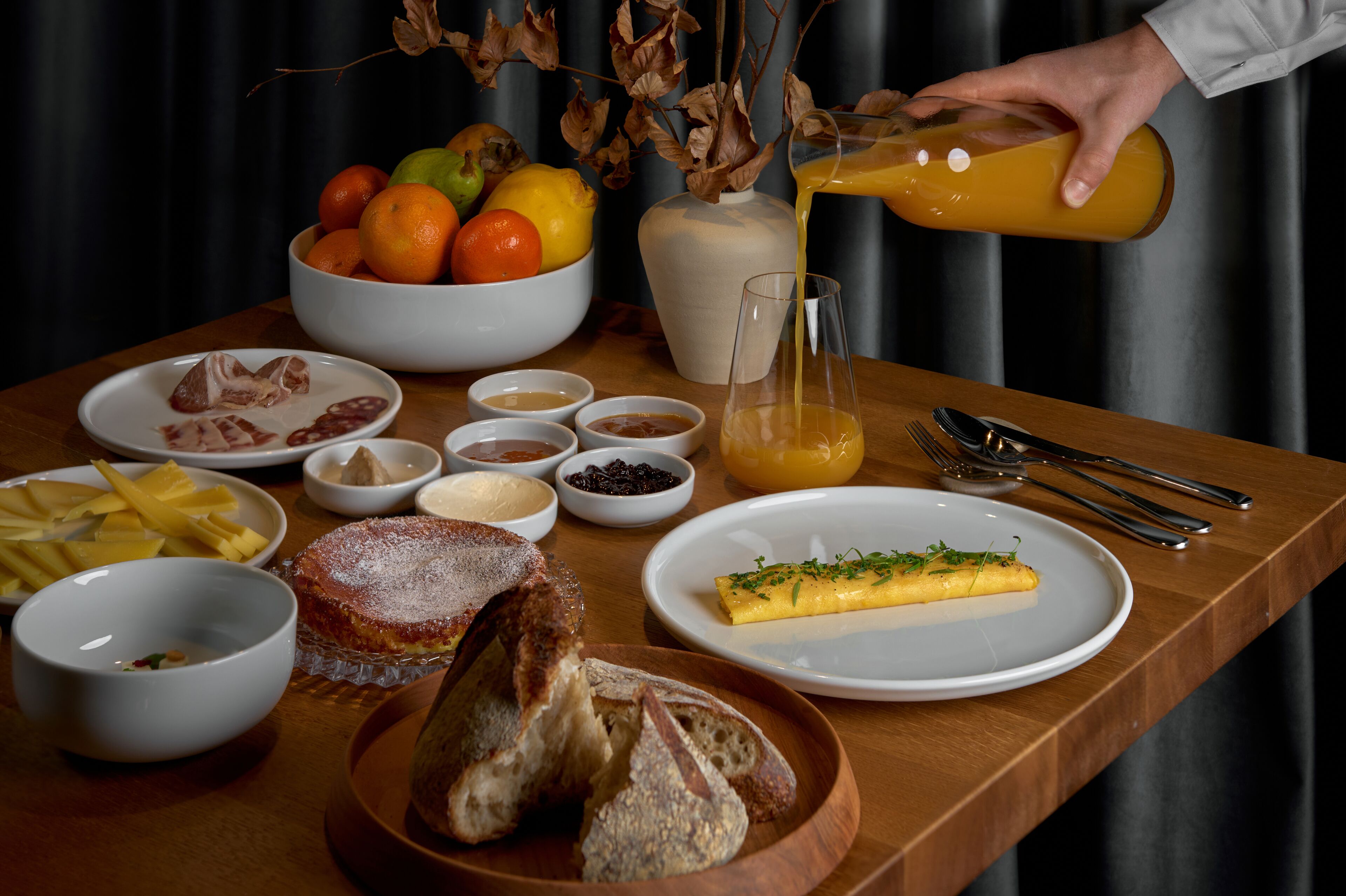 Ein Frühstückstisch mit verschiedenen Speisen, darunter Obst, Brot und Beilagen.