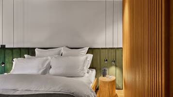 Un dormitorio moderno con cama, ropa de cama blanca, una mesita de noche de madera y un cabecero verde.