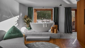 A modern bathroom with a freestanding bathtub, a large window, and a view of a forest. - Boutique Hotel and Restaurant Milka (Kranjska Gora)