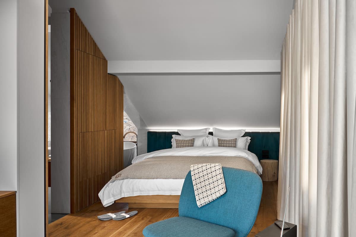 Une chambre à coucher moderne avec un lit, une chaise bleue et une cloison en bois.