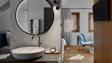 Un baño moderno con un espejo redondo grande, un lavabo blanco y un mueble de tocador de madera.