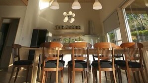 A dining area with wooden chairs and a table, a wooden ceiling, and pendant lights. - I Sky Villa (Zaoqiao)