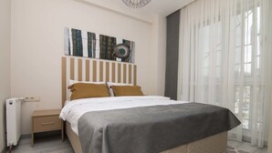 Une chambre d’hôtel bien rangée, avec un lit, une table de chevet et un radiateur.