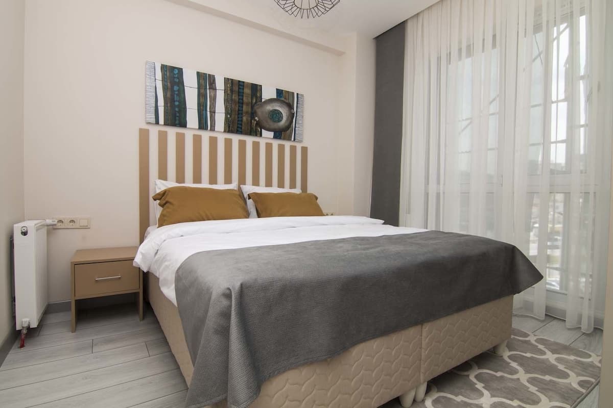 A neatly arranged hotel room with a bed, bedside table, and a radiator.