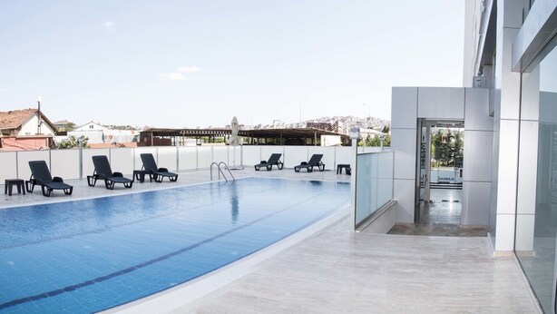 Une piscine sur le toit, dotée de chaises longues et d’une entrée en verre.