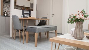 Une cuisine moderne avec un coin repas, comprenant une table en bois, des chaises à revêtement gris et un vase avec des fleurs.