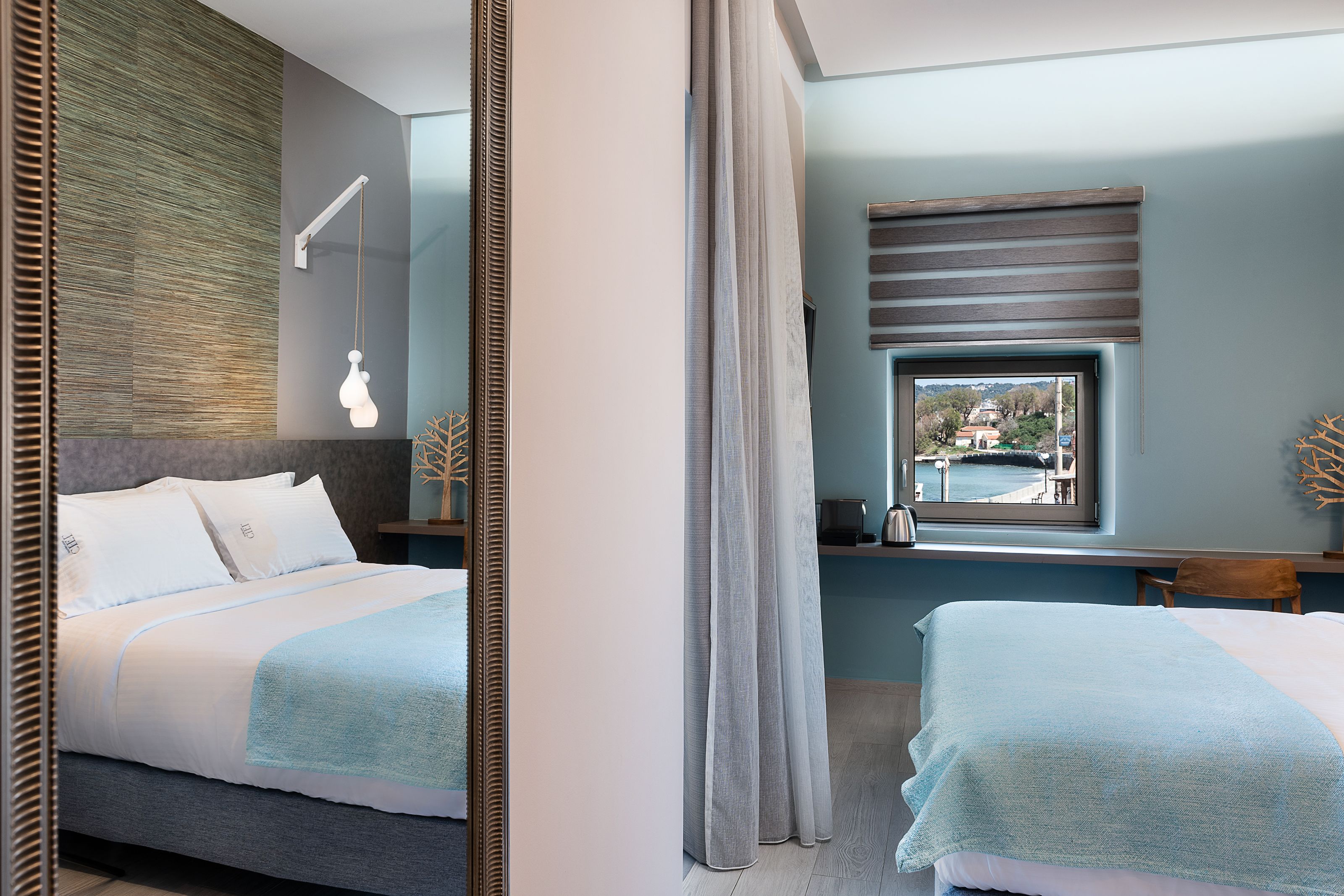 Een moderne hotelkamer met een groot bed, nachtkastje, raam met uitzicht en een spiegel.