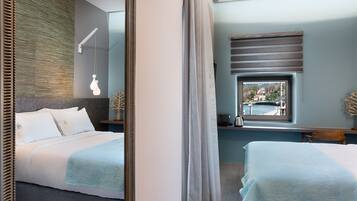 A modern hotel room with a large bed, a bedside table, a window with a view, and a mirror.