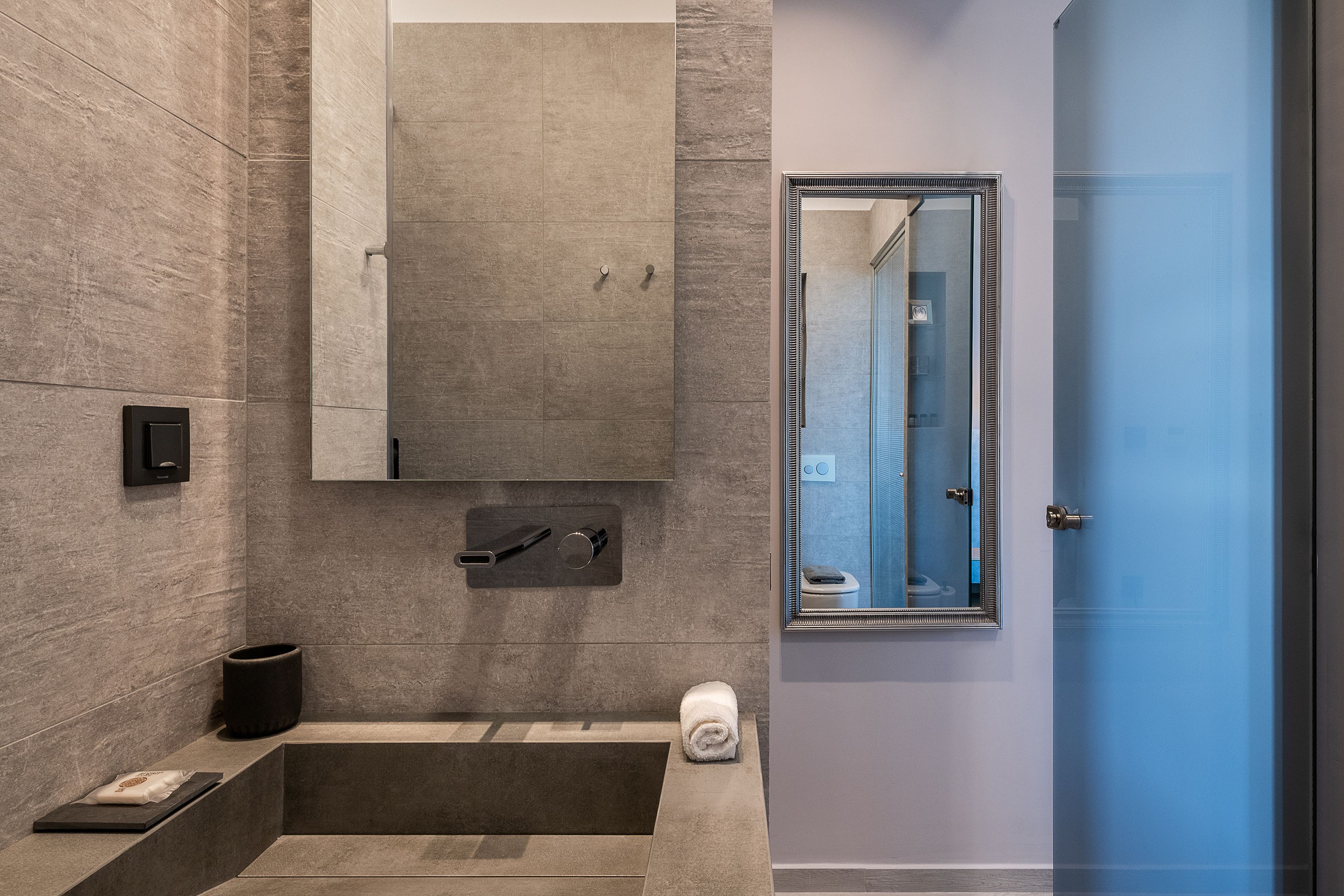 Une salle de bain moderne avec une grande baignoire, un miroir fixé au mur et une cabine de douche en verre.