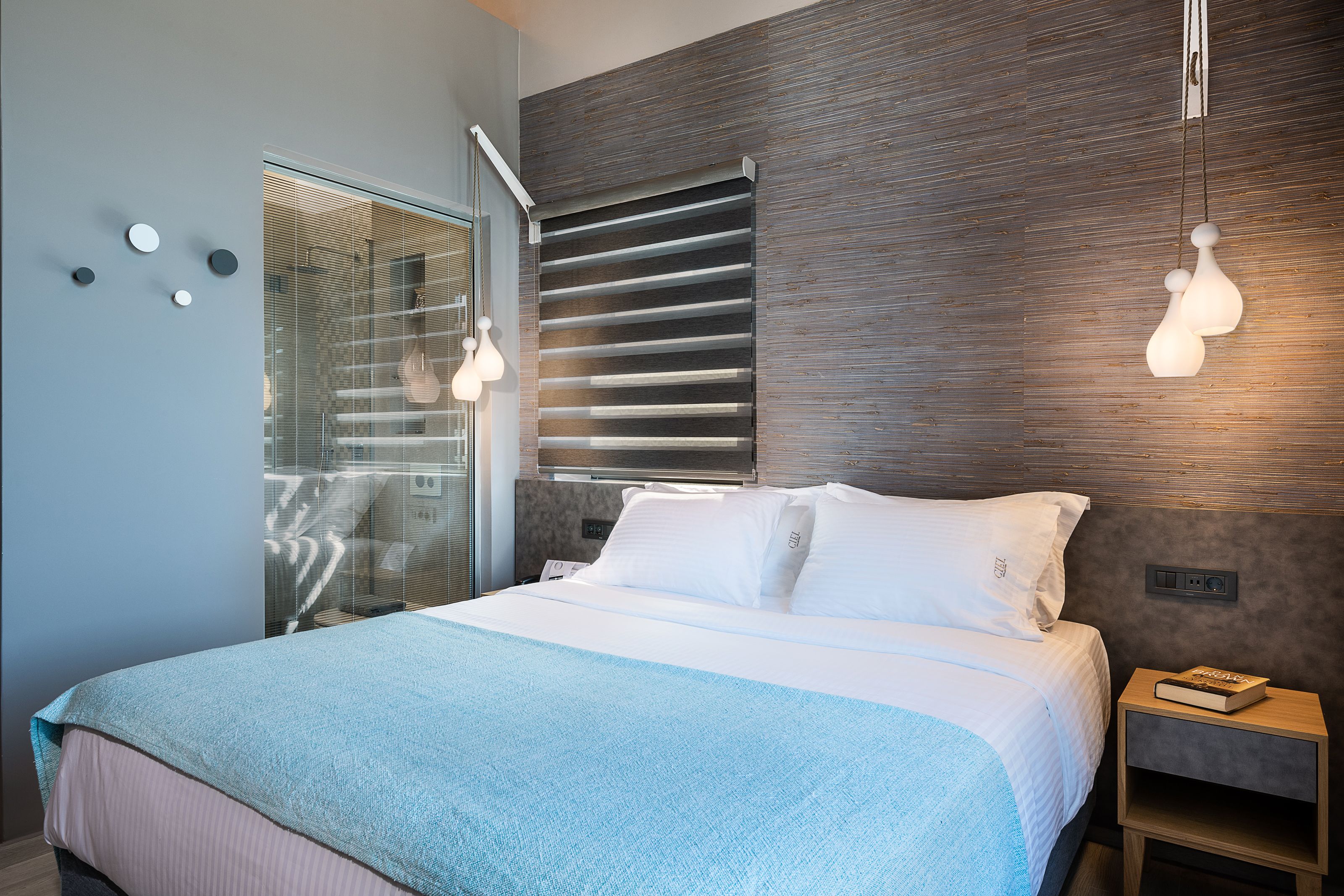 Une chambre moderne avec un grand lit, une table de chevet et une fenêtre équipée de stores.